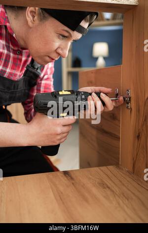Furniture assembly using drill screwdriver at home. female handyman Stock Photo