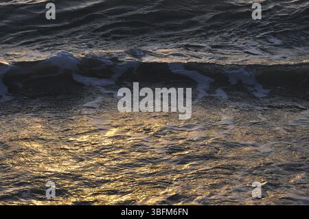 Golden sunset reflections on waves creating an enchanting scene, Waves of the Mediterranean Sea in Sicily Stock Photo