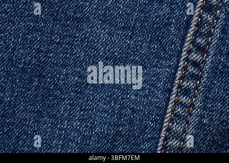 abstract background: close up seam with orange thread on dark blue jeans Stock Photo