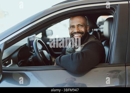 Portrait of happy man with shaved head sitting in car Stock Photo
