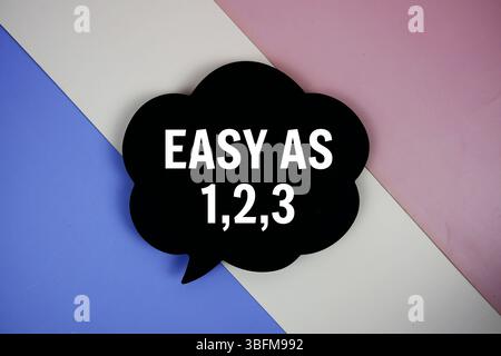 EASY AS 1,2,3 text on speech bubble top view on purple geometric background Stock Photo