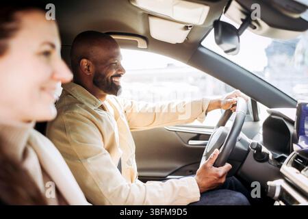 Happy man driving car while talking with woman during road trip Stock Photo