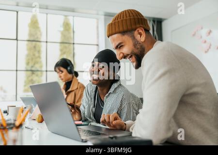 Happy male and female business professionals laughing while working together at office Stock Photo