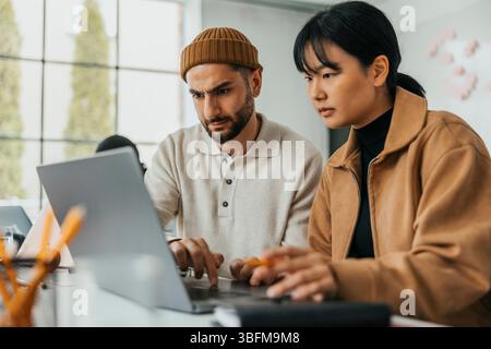Focused male and female business professionals working together on laptop at office Stock Photo
