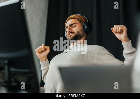 Tired computer programmer stretching while sitting in tech start up office Stock Photo
