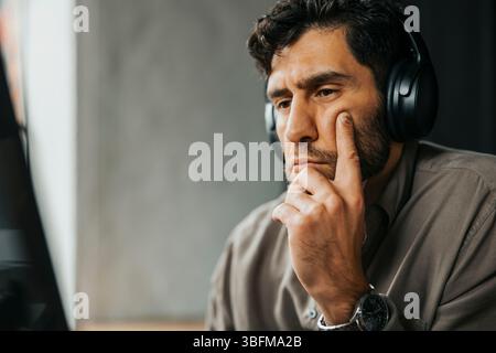 Focused male computer programmer with wireless headphones working at office Stock Photo