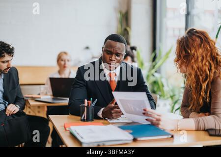 A business meeting in a co-working space featuring a discussion among diverse people Stock Photo
