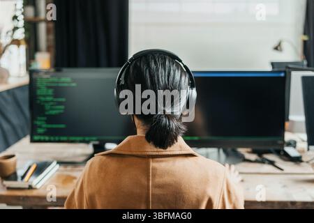 Rear view of computer programmer with ponytail doing coding at tech start up office Stock Photo