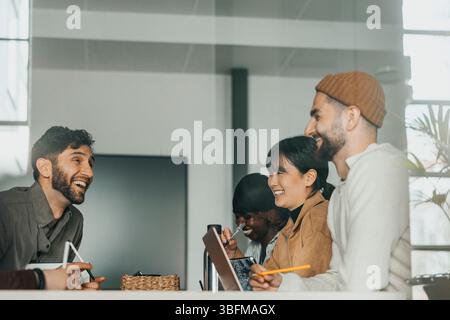 Team of happy male and female business professionals in office seen through glass Stock Photo