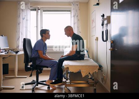 Doctor talking to patient sitting on examination table Stock Photo