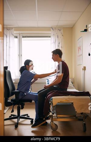 Doctor examining patient with stethoscope in clinic Stock Photo