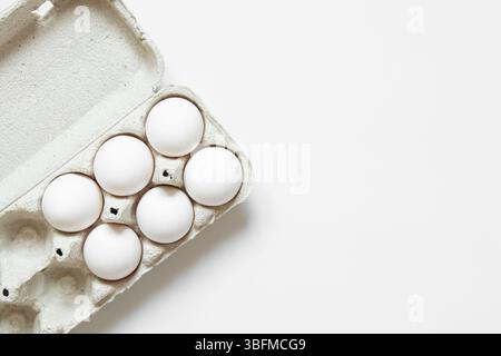White chicken eggs in a cardboard box on a white background close-up Stock Photo
