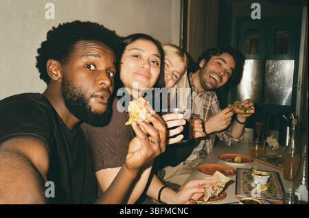 Portrait of young man taking selfie with friends while eating tacos at restaurant Stock Photo