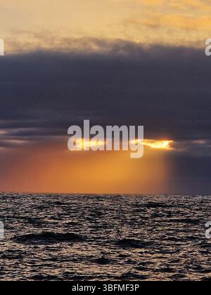 Dramatic Sunset "eyes" Over Ocean With Vibrant Colors and Cloudy Sky. Brighton, UK Stock Photo
