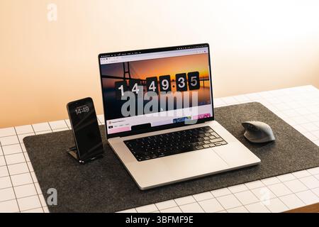 Clean and organized desk setup featuring a laptop with an on-screen countdown timer, smartphone, and mouse on a felt mat. Ideal for illustrating conce Stock Photo