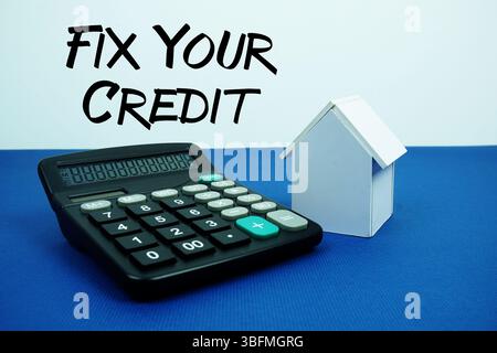 Fix Your Credit text with White house model with calculator on navy blue background, mortgage and properties concept Stock Photo