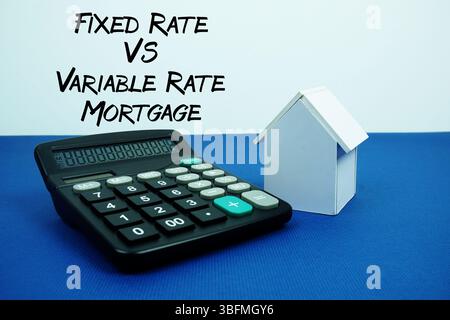 Fixed Rate Vs Variable Rate Mortgage text with White house model with calculator on navy blue background, mortgage and properties concept Stock Photo