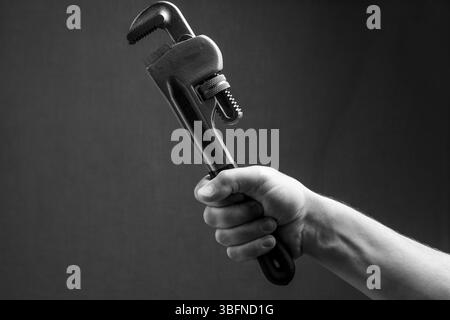 Adjustable wrench in hand on dark background. Black and white photo Stock Photo