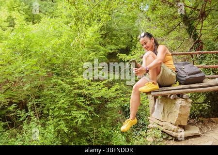 Woman using smartphone for pathfinding in forest Stock Photo