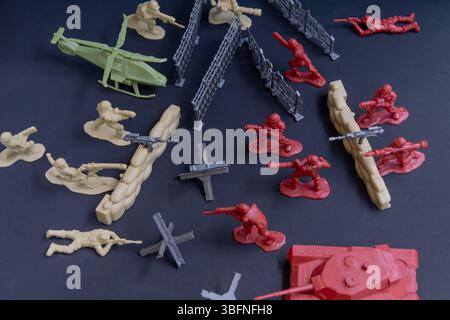 Miniature battle - concept of military aggression. Plastic figures of soldiers of opposite sides on the background of defence fortifications. Concept Stock Photo
