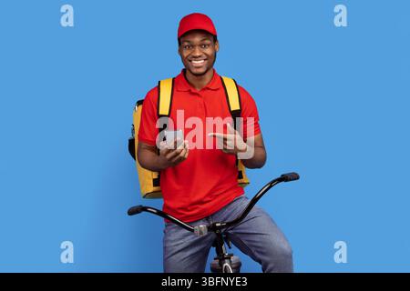 Black delivery man riding bicycle, using smartphone Stock Photo