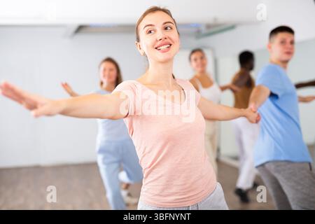 Smiling young adult couples dancing together in pairs and practicing movements in modern choreography class Stock Photo