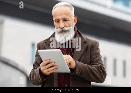 Wealthy senior man using digital tablet outdoors Stock Photo