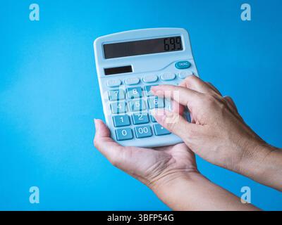 Woman using calculator, close up view. Isolated on blue background. Stock Photo