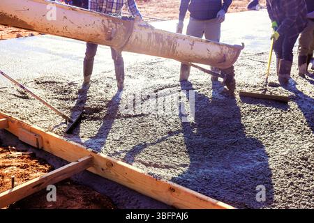 Construction crew expertly pours fresh concrete slab to create strong foundation for new building during works day Stock Photo