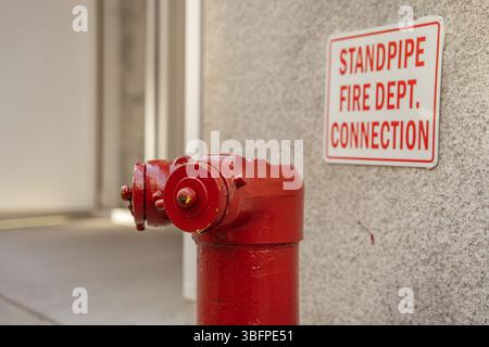 A red fire hydrant stands next to a wall-mounted emergency sign. The image emphasizes urban safety infrastructure in New York City. Stock Photo