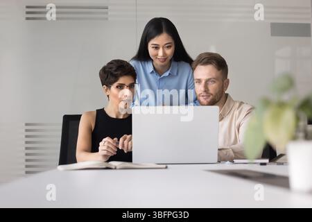 Three teammates using laptop engaged in teamwork in modern office Stock Photo