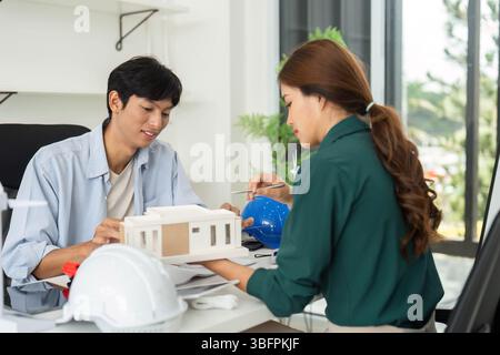ESG and Sustainability. Young architects discussing building model in modern office. Stock Photo