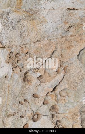 Close-up of a beautiful curved shapes on a sculpted granite rock surface, viewed from above on a sunny day. Abstract natural textured background. Stock Photo