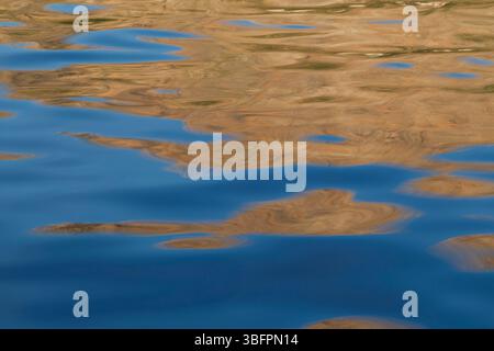 Abstract blue and brown reflections on rippled water surface. Background with abstract natural shapes and vibrant colors. Stock Photo