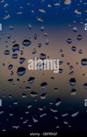 Raindrops on the window against the background of the setting sun. Background with glass and drip texture. High quality photo Stock Photo
