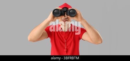 Male lifeguard with binoculars on grey background Stock Photo