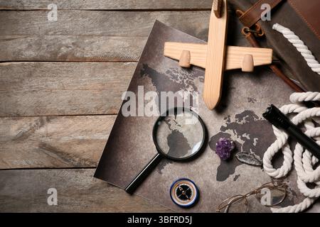 Bag with travel equipment, world map, mineral stones and airplane toy on brown wooden background Stock Photo