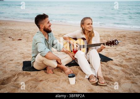 A Happy Couple Enjoying Music Together on the Beautiful Beach During Sunset Moments Stock Photo