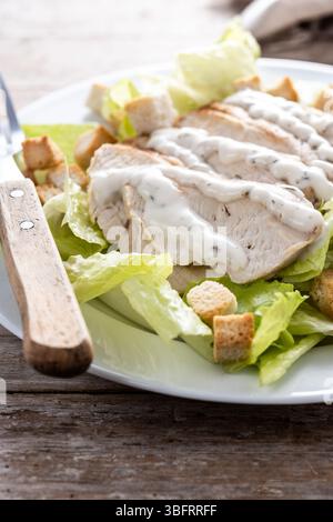Crunchy Caesar salad with chicken on wooden table Stock Photo