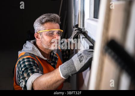 Close-up of a skilled worker using a spirit level to ensure precise horizontal alignment of a newly installed window on a construction site Stock Photo