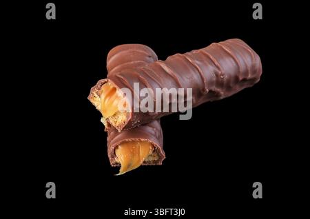 Unwrapped chocolate snack bar on black surface, unhealthy treat Stock Photo
