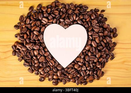 White wooden heart lying on coffee beans pile Stock Photo