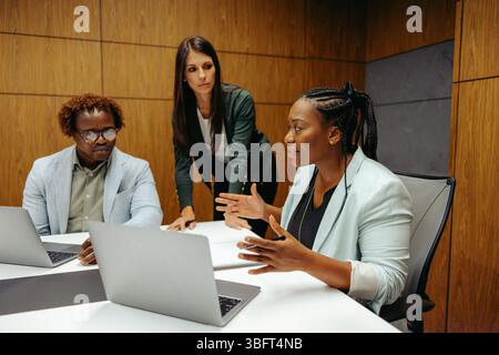 A group of accountants engaged in a professional discussion about a client project. The team, consisting of two men and a woman, collaborates at a con Stock Photo
