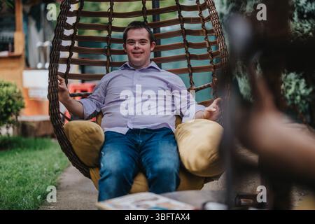 Young man with Down syndrome enjoying a swing chair outdoors Stock Photo