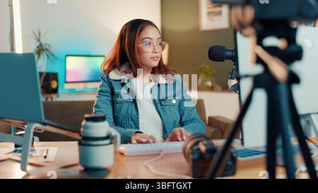 Woman, designer and typing on computer for photo editing or content creation at home. Female person, freelancer or podcaster with technology or mic Stock Photo