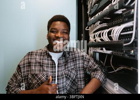 Young technician smiling confidently while working in server room Stock Photo
