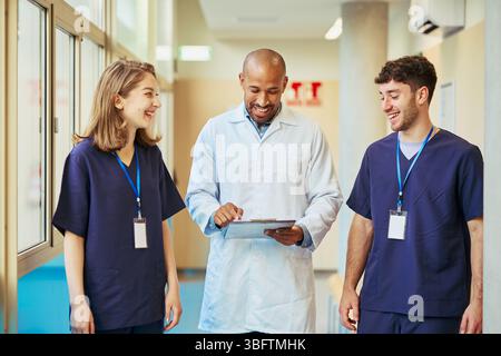 Medical team discussing patient information while walking in hospital corridor Stock Photo