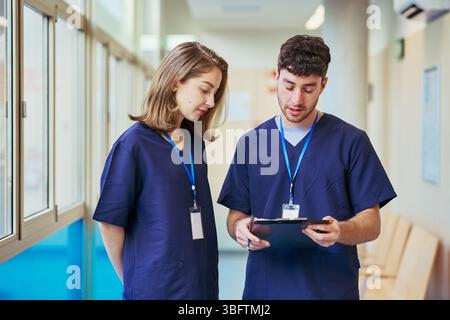 Medical professionals collaborating: analyzing patient records in hospital hallway Stock Photo