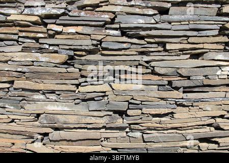 A wall made of thin and tall rubble stones. Stone wall detail for backgrounds. Stock Photo