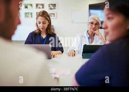 Medical team collaborating on patient care in hospital meeting Stock Photo